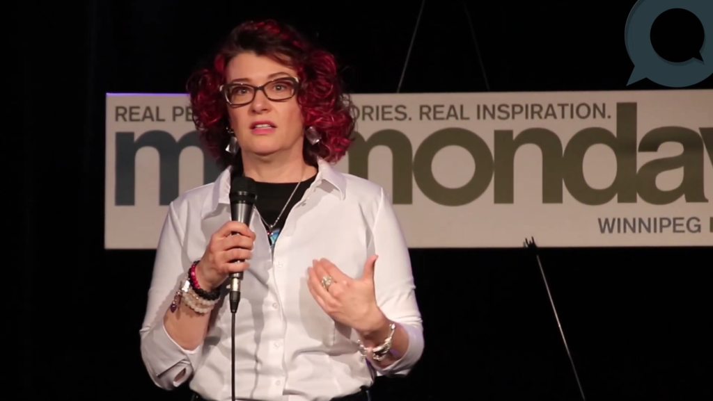 Image of Sharon Blady on stage speaking at Momonday.
